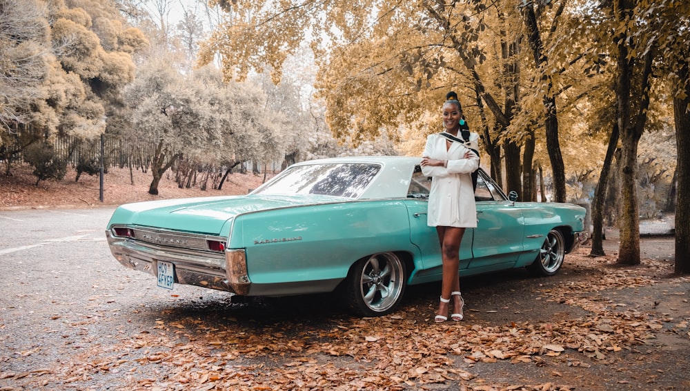 a woman standing next to a turquoise car