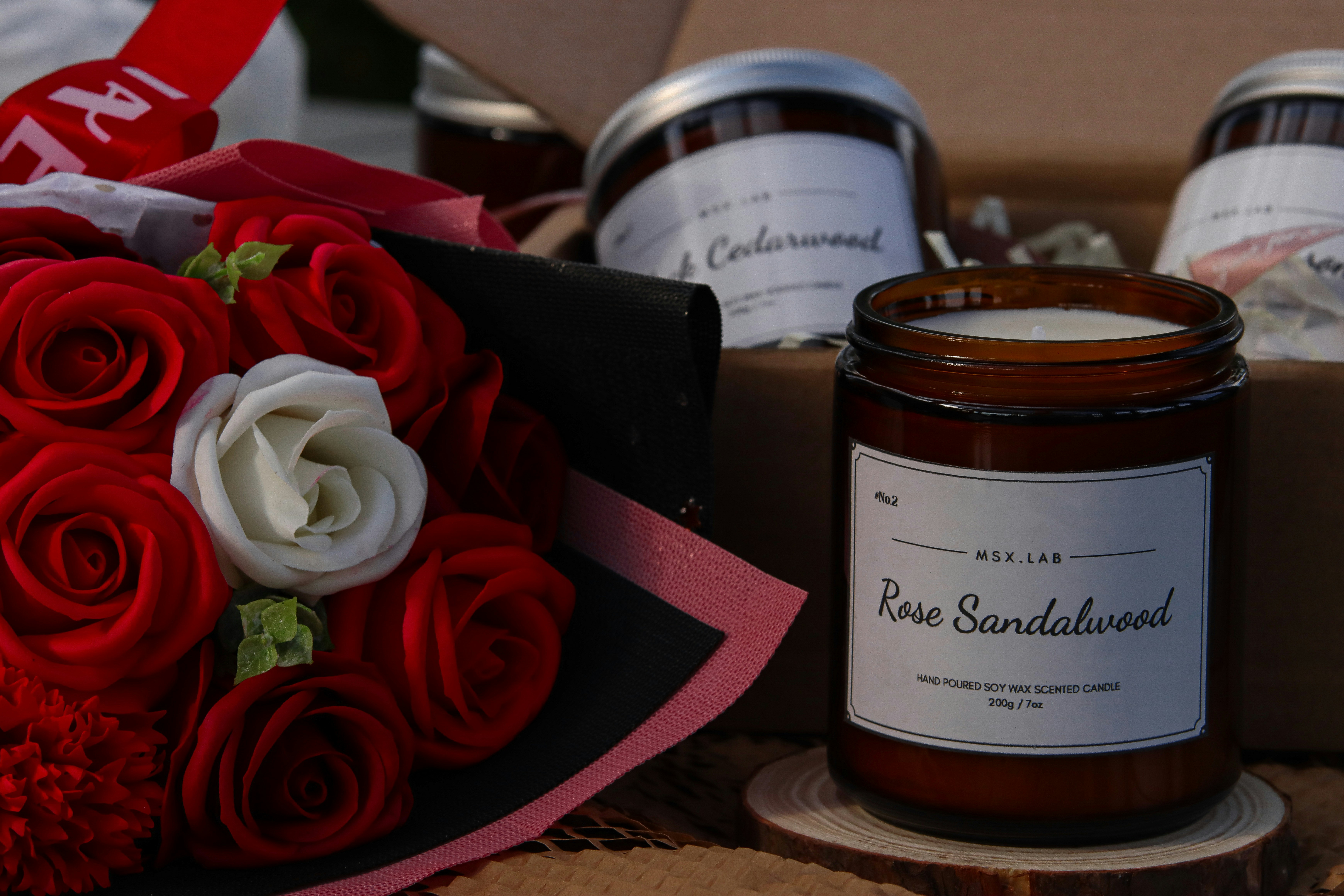 a bouquet of red and white roses next to a candle