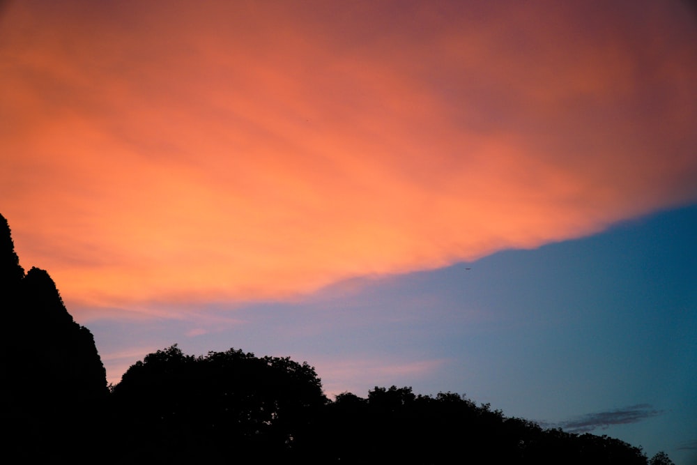 a red sky with some clouds and some trees