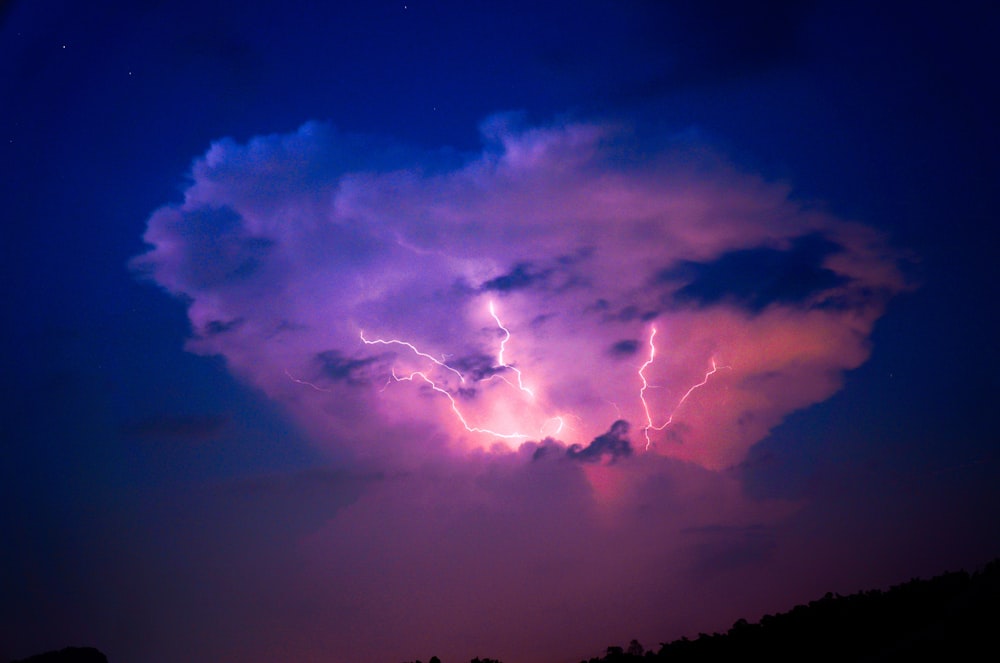 a purple and blue cloud with lightning in the sky