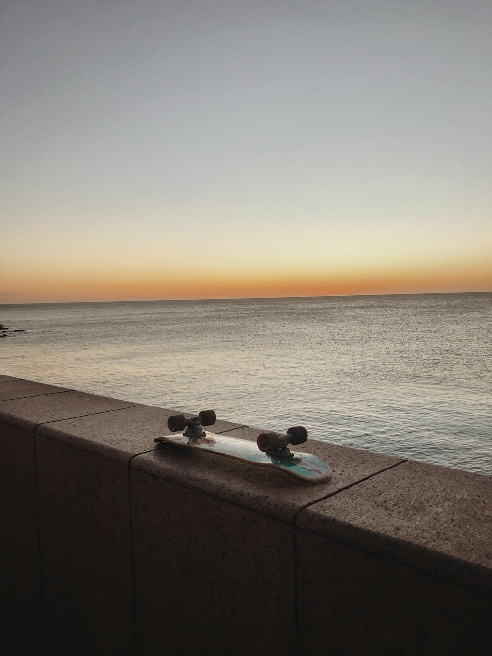 a skateboard sitting on a ledge next to the ocean