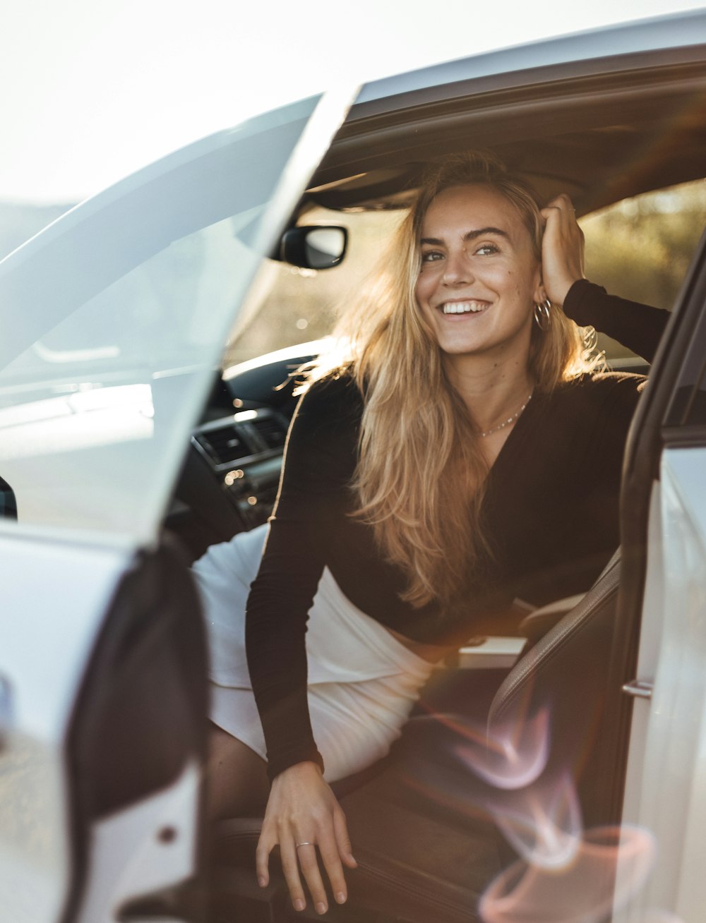 uma mulher sentada em um carro sorrindo para a câmera