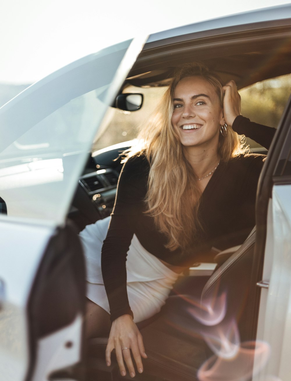 Une femme assise dans une voiture souriant à la caméra