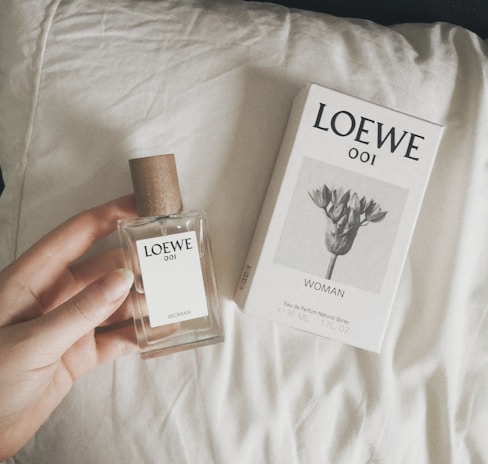 a person holding a bottle of cologne next to a box of cologne