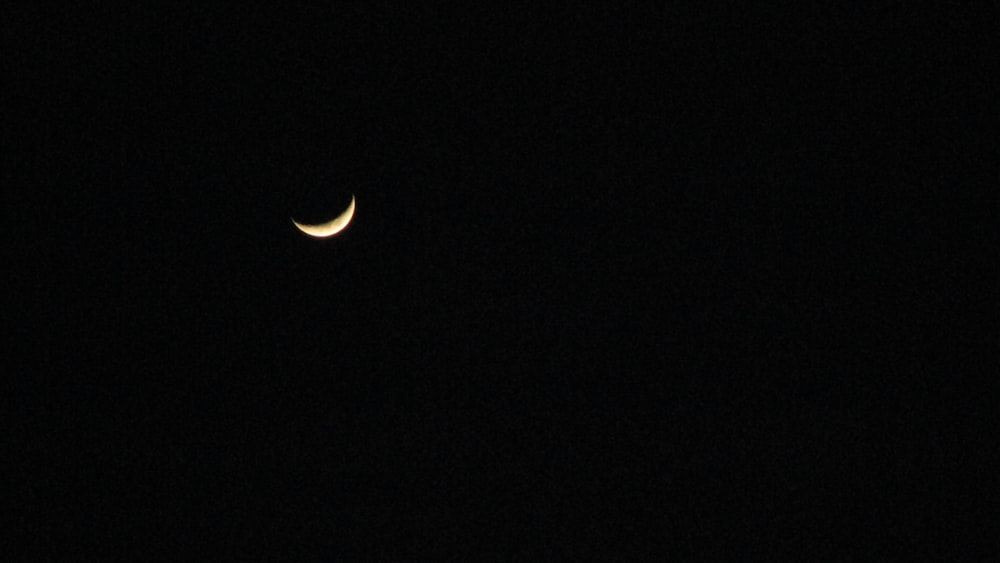 a crescent moon is seen in the dark sky