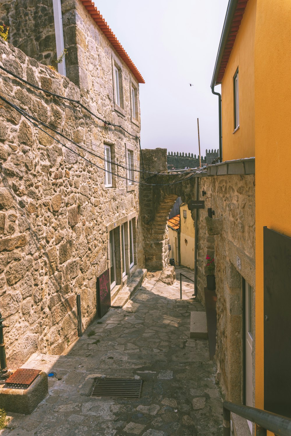 a narrow alley way with a yellow building in the background