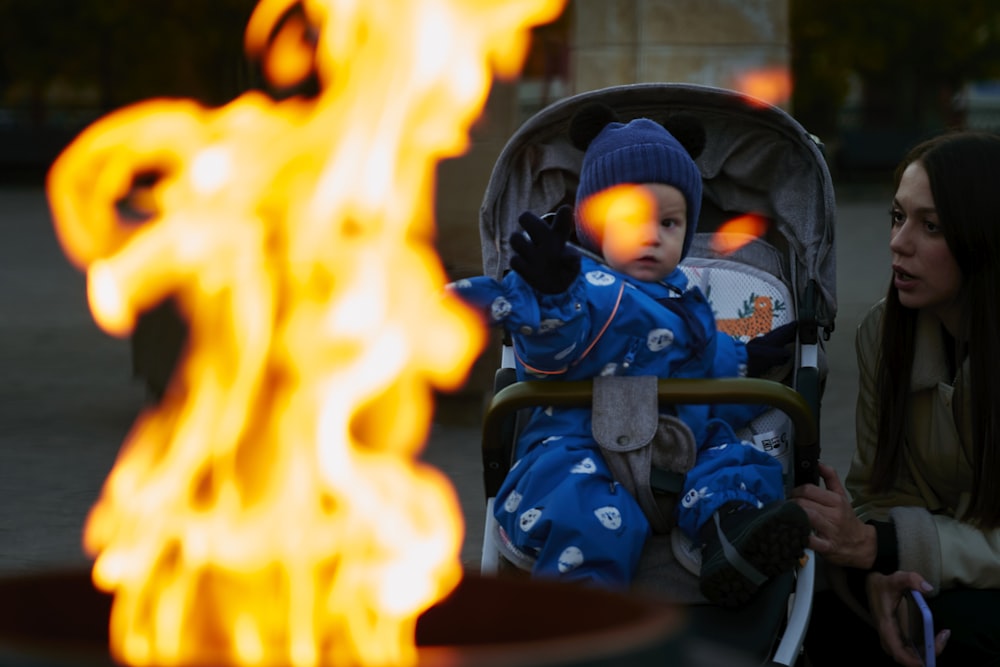 a baby in a stroller sitting in front of a fire