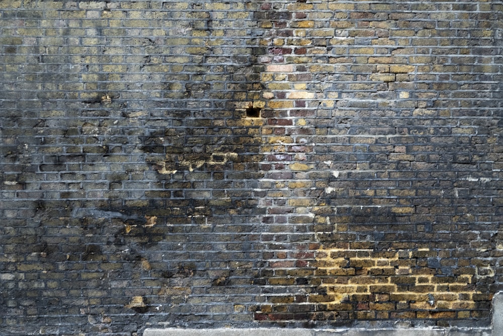 a person sitting on a bench in front of a brick wall