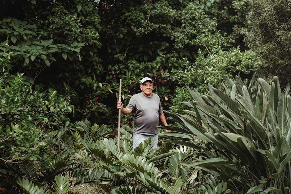 a man standing in a forest holding a stick