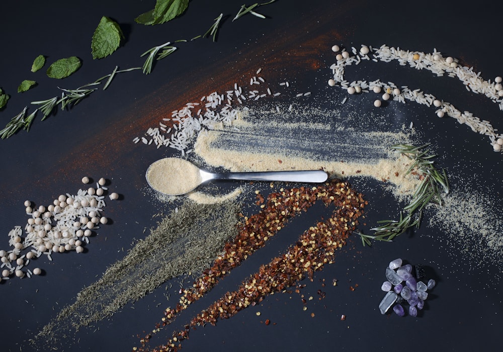 a spoon full of spices next to a pile of spices