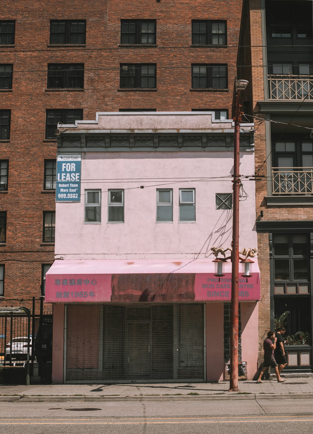 a pink building with a pink awning on a city street