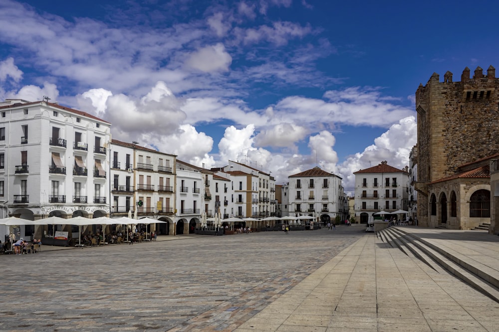 a street lined with white buildings under a cloudy blue sky