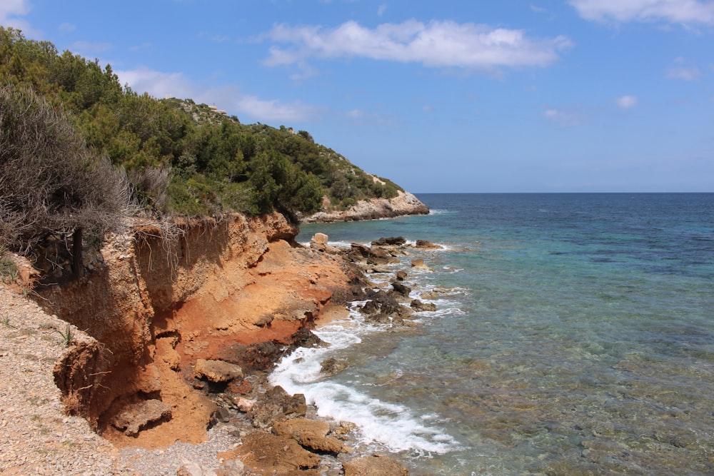 a rocky shore line with clear blue water