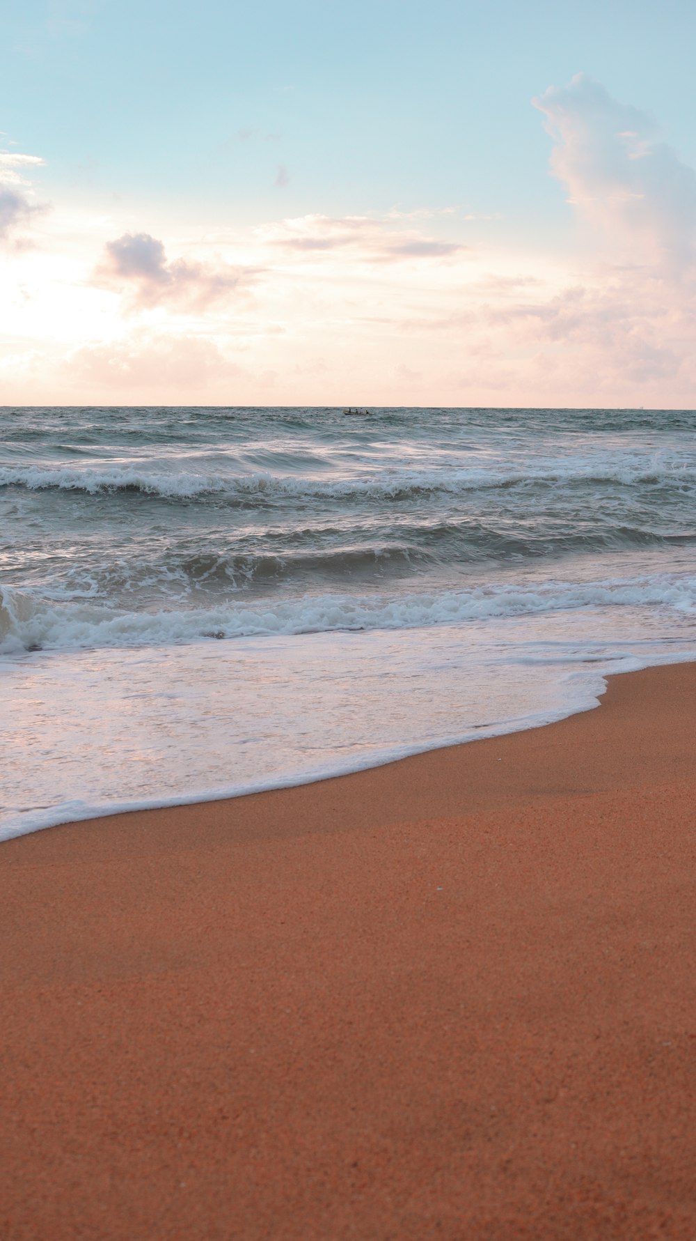 a sandy beach with waves coming in to shore