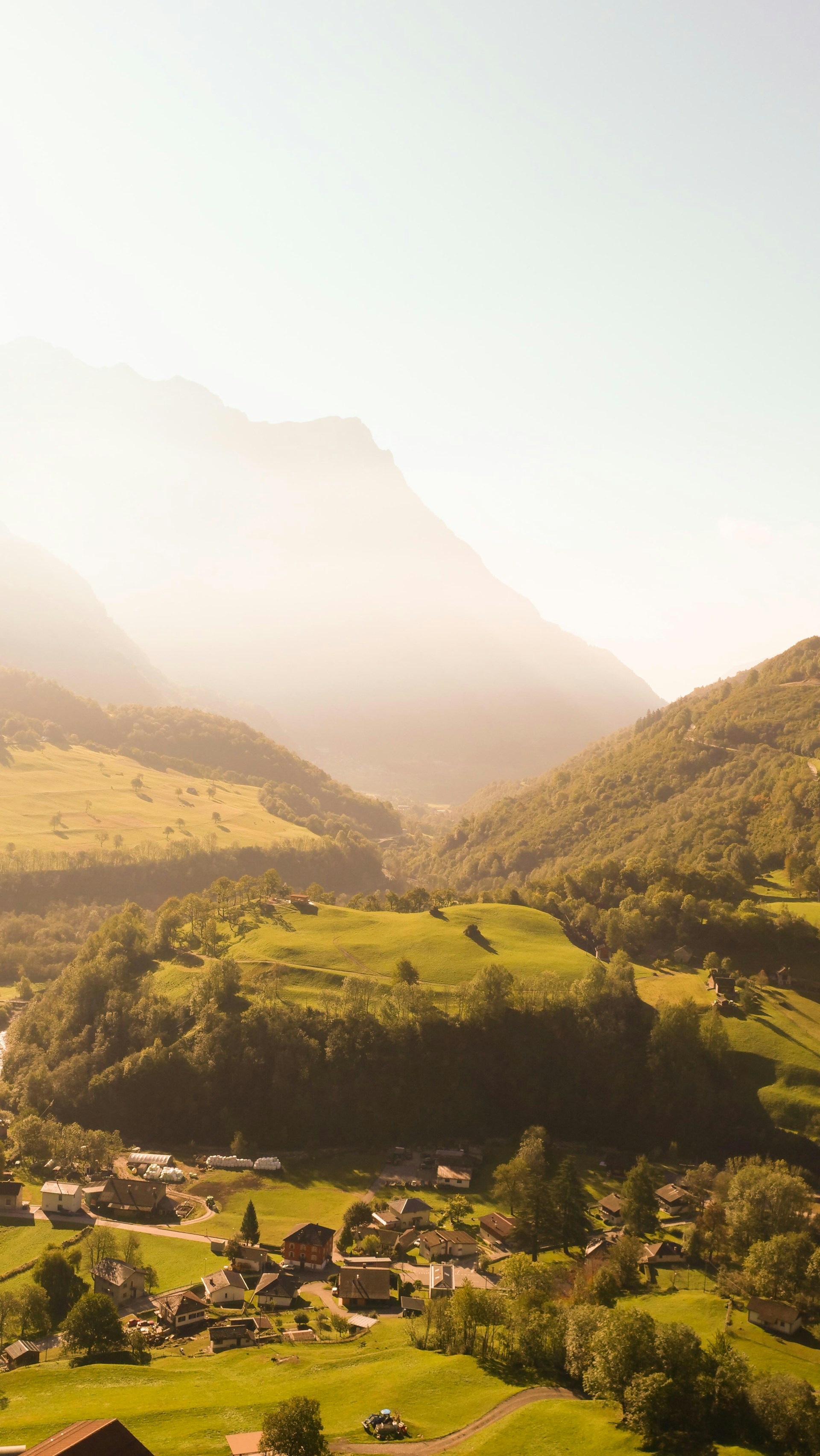a scenic view of a valley with houses and mountains in the background