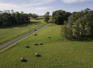 a car driving down a country road surrounded by hay bales