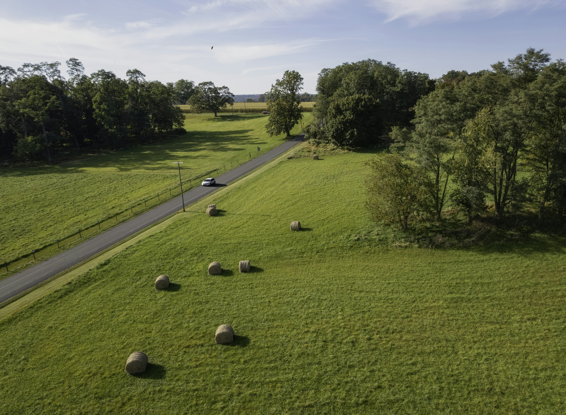 a car driving down a country road surrounded by hay bales