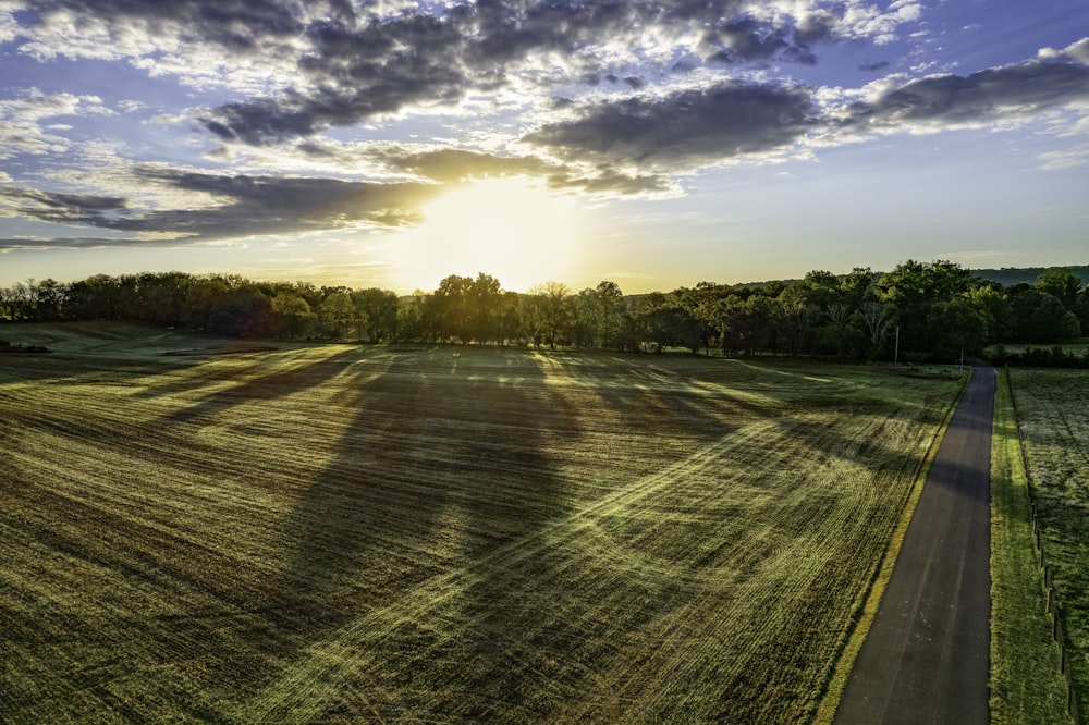 the sun is setting over a field of grass