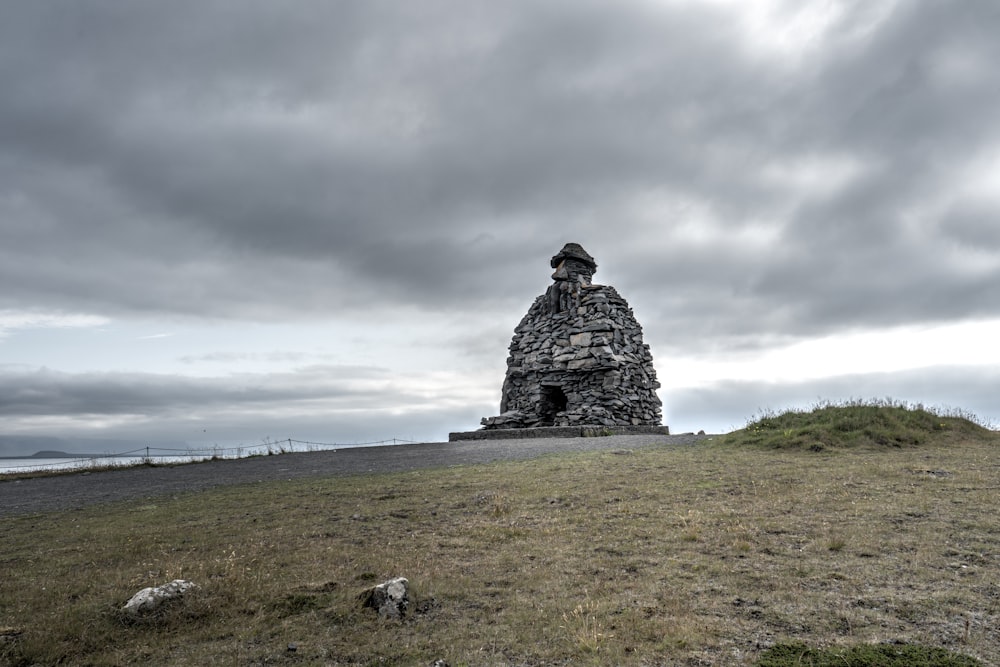 una struttura in pietra seduta sulla cima di una collina coperta di erba