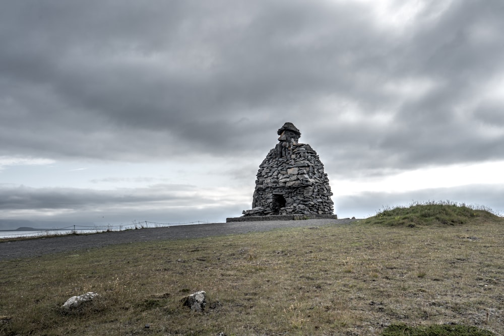 a stone structure sitting on top of a grass covered hill