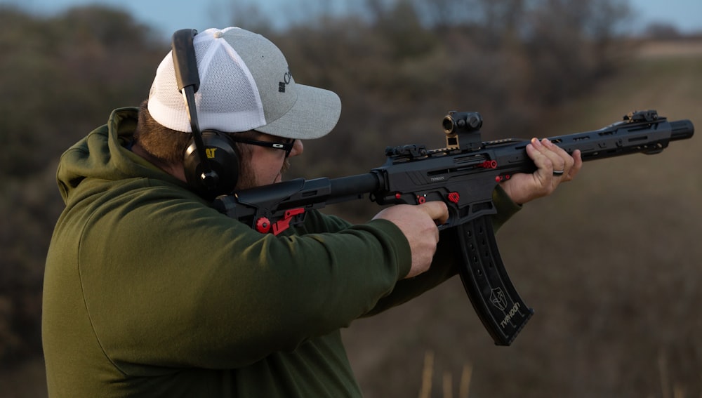 a man holding a rifle and wearing a hat