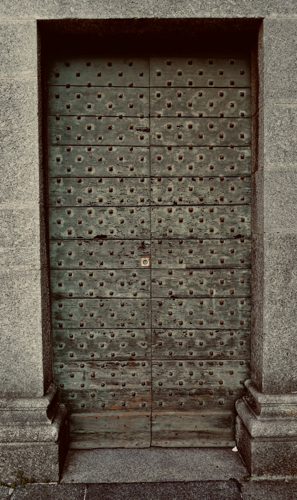 a large metal door with a bench in front of it