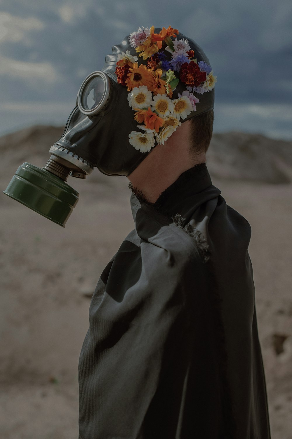 a man wearing a gas mask with flowers on his head