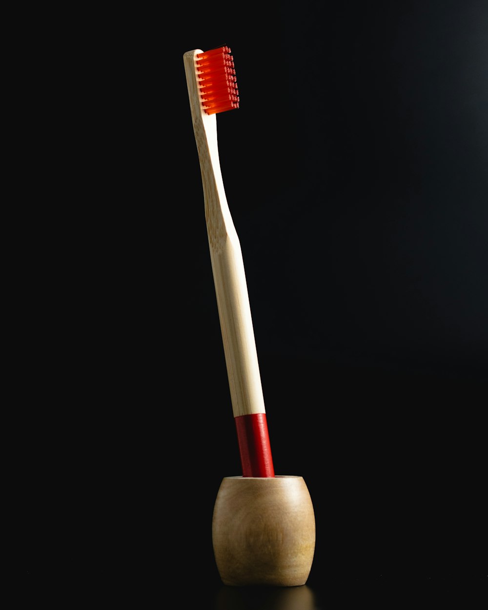 a wooden toothbrush holder with a red toothbrush in it