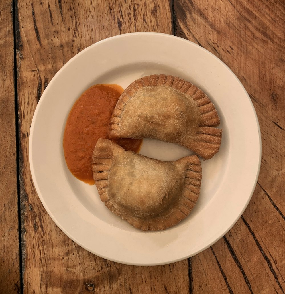 a white plate topped with two pastries covered in sauce