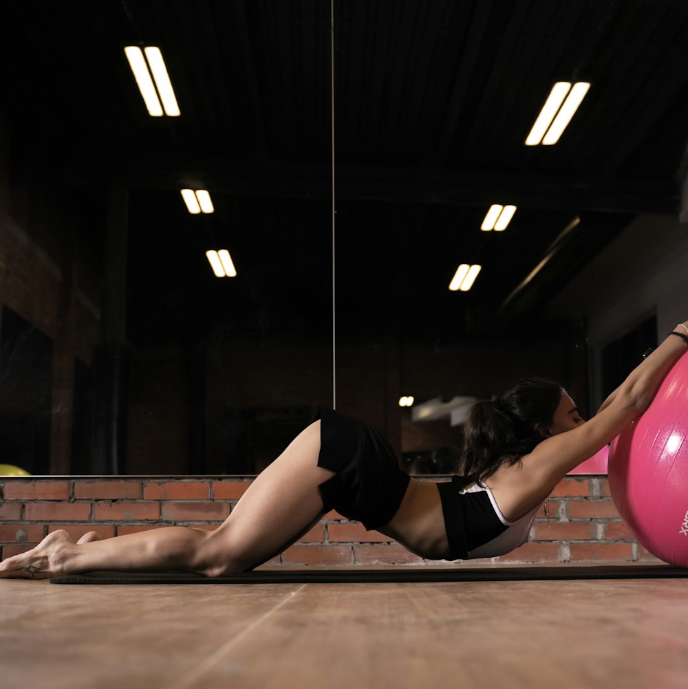 a woman doing exercises on a pink exercise ball