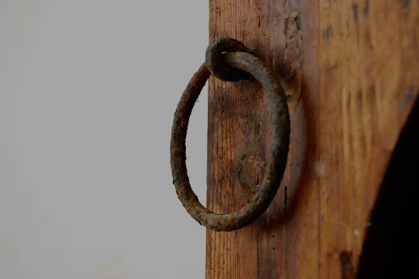 Close-up of a handcrafted rustic door handle with a weathered finish on a reclaimed wood door.