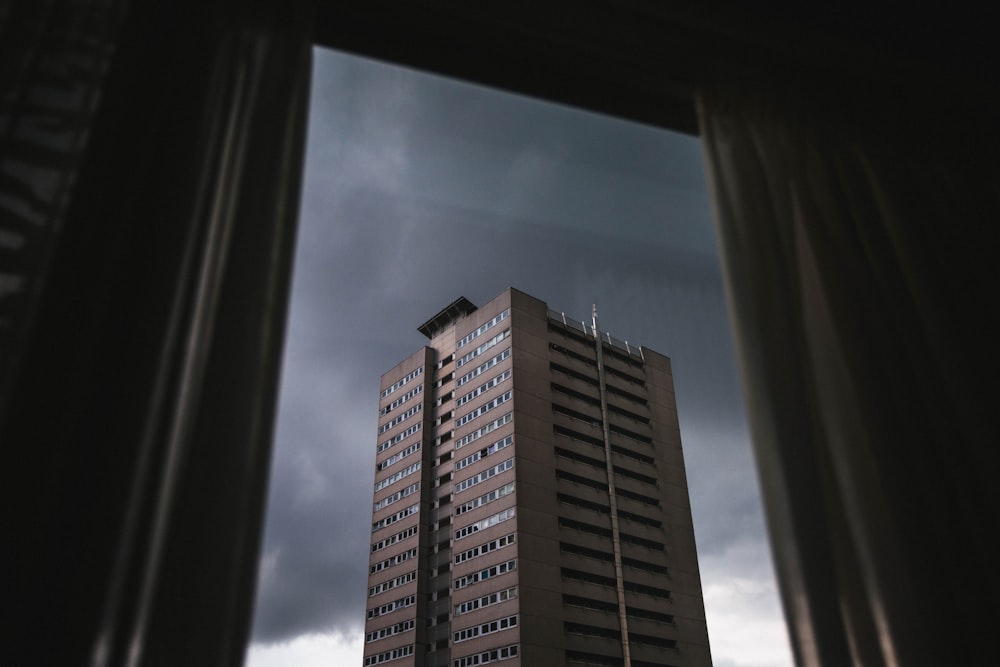 a tall brown building sitting next to a cloudy sky