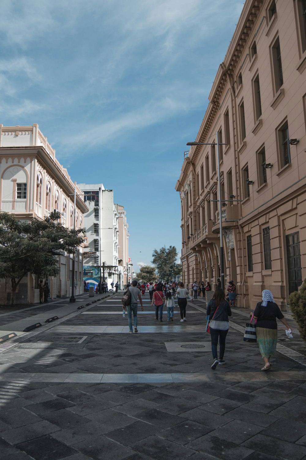 a group of people walking down a street next to tall buildings