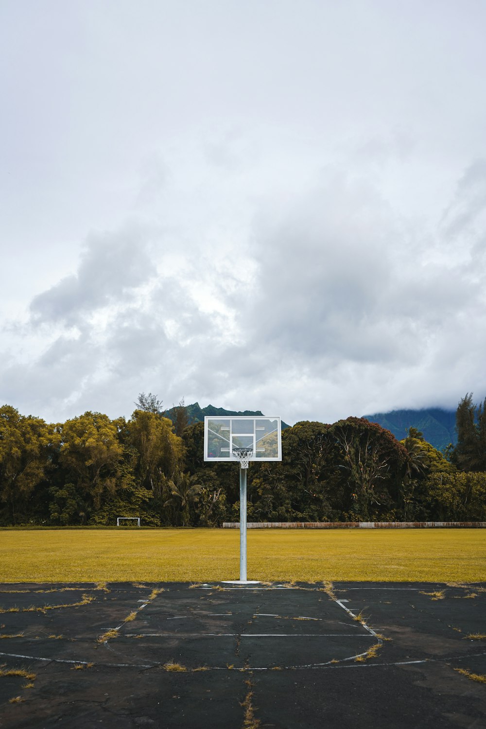 a basketball hoop in a parking lot with mountains in the background