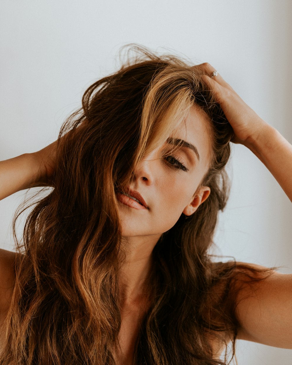 a woman with long brown hair holding her head