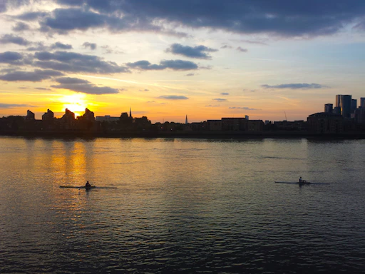 A vibrant sunset over Kawartha lakes with kayakers paddling near the shore.