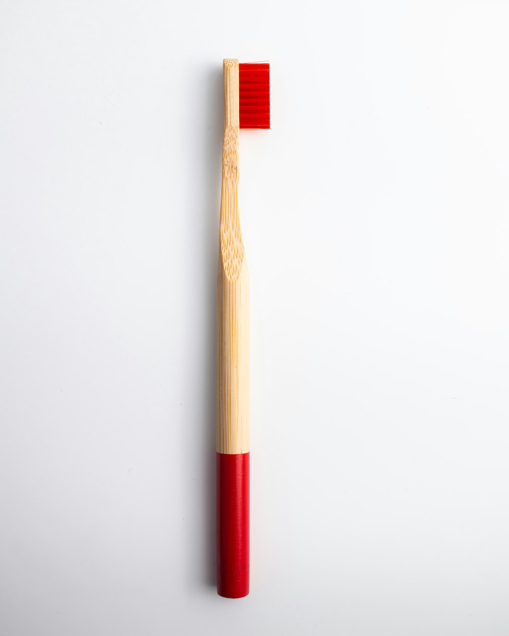 a wooden toothbrush with a red bristles on a white background