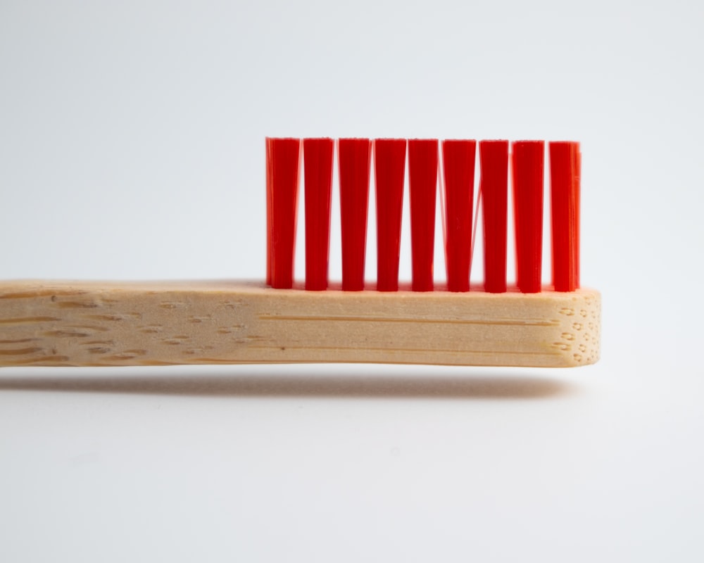 a red toothbrush sitting on top of a wooden holder