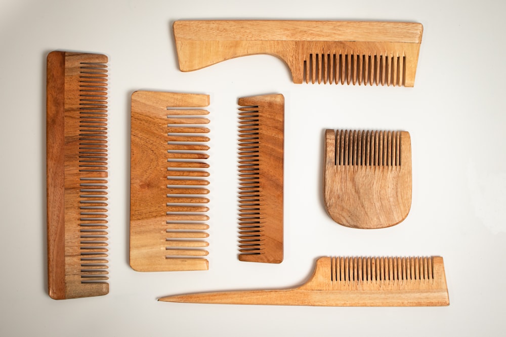 a collection of wooden combs and combs on a white surface