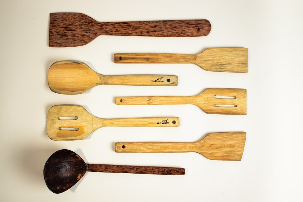 a group of wooden spoons and spatulas on a white surface