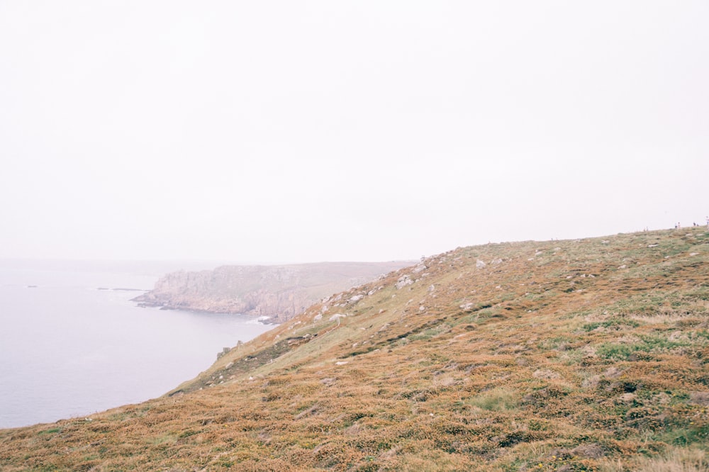 a person sitting on a hill overlooking the ocean