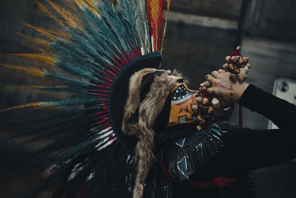 a person with a headdress and feathers on