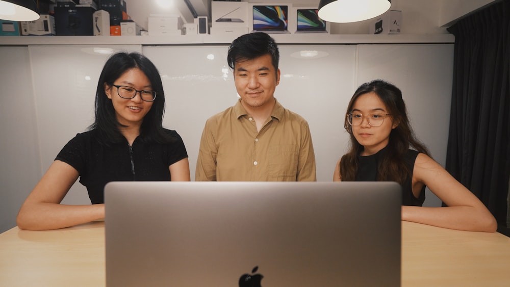 a group of three people standing in front of a laptop