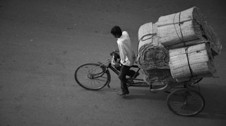 a man riding a bike with a load of hay on the back of it