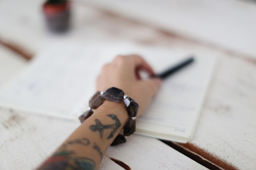 a person writing on a piece of paper with a pen