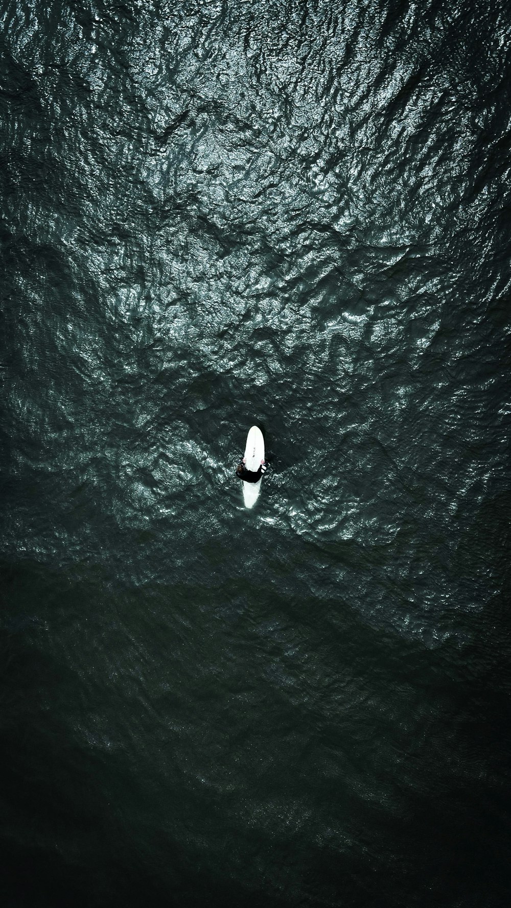 a lone white surfboard floating in the middle of the ocean