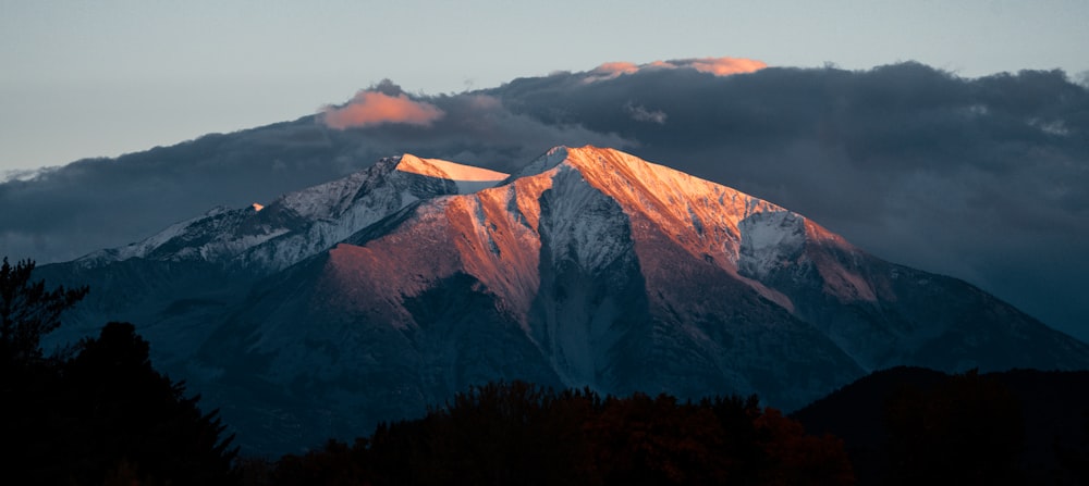 a large mountain covered in snow under a cloudy sky