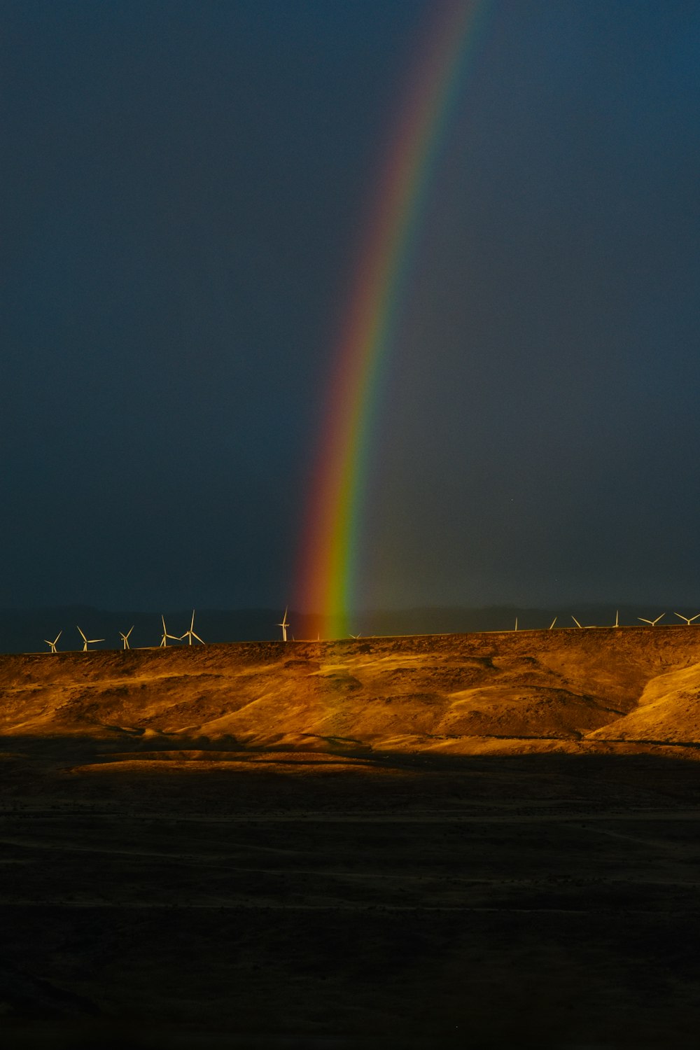 a rainbow shines in the sky over a desert landscape