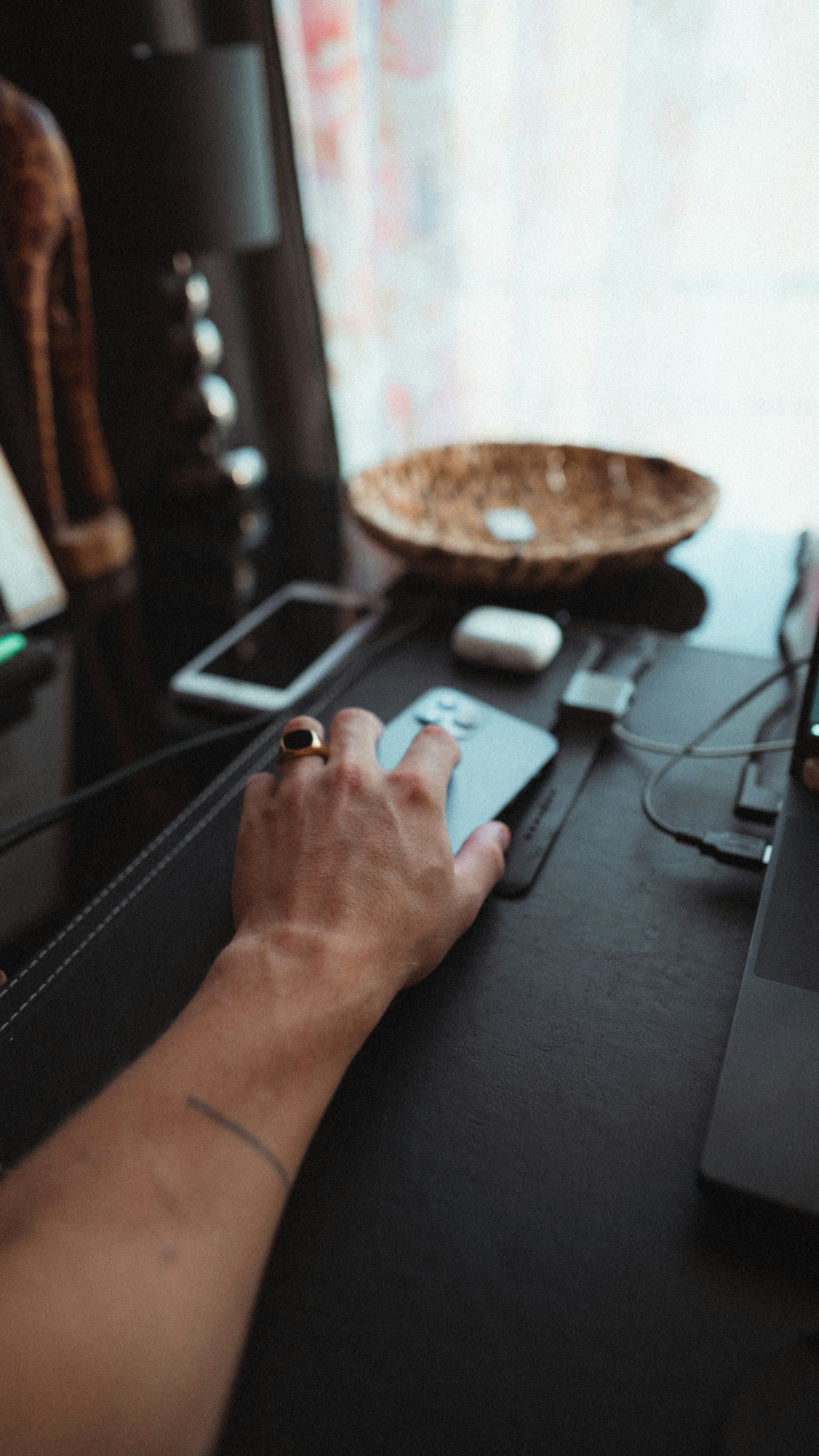 Main tendant la main vers un smartphone sur un bureau de bureau encombré.