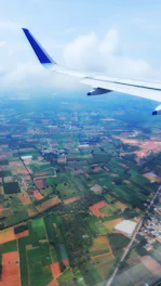 A calm aerial view at dusk showing a plane cruising above a patchwork of fields.